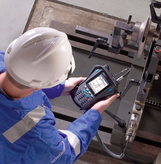 Técnico realizando análise de vibração com coletor em equipamento industrial